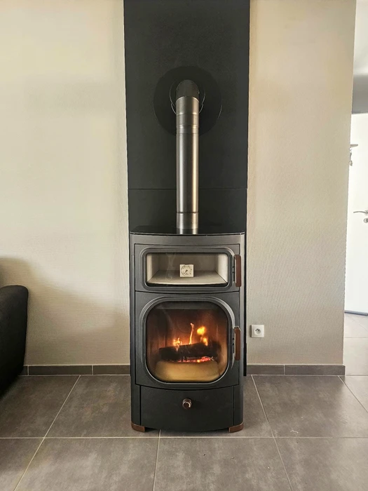 Photographie en gros plan d'un détail de poêle à granulés moderne : vue rapprochée du système de chargement automatique du foyer avec pellets visibles, mettant en évidence la technologie et la précision mécanique de l'équipement. Environnement intérieur résidentiel, éclairage professionnel mettant en valeur les détails techniques de l'installation.