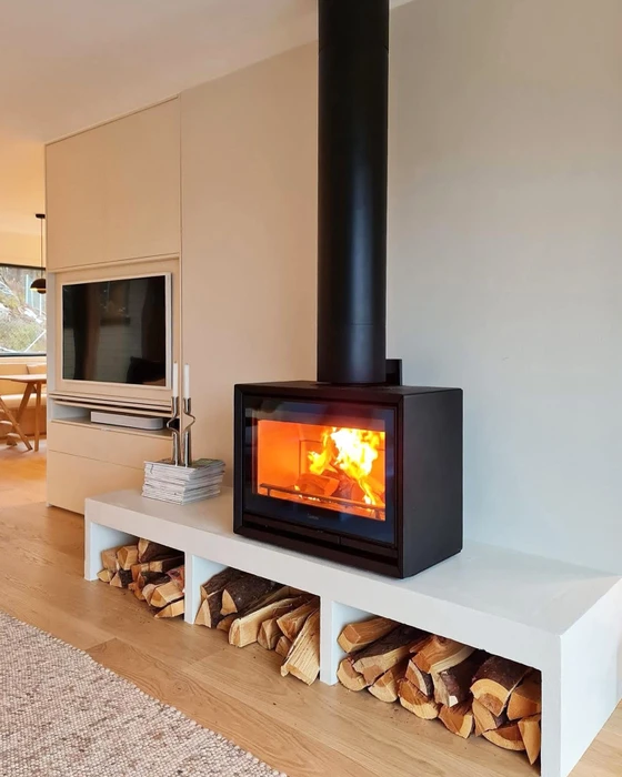 Intérieur chaleureux avec poêle à bois en fonte noire à foyer ouvert, flammes vives visibles derrière vitre arquée