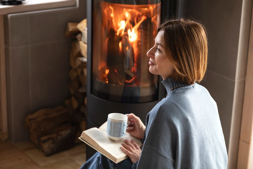 Intérieur résidentiel avec poêle à bois en fonte noire allumé, flammes orange visibles derrière vitre ornementale