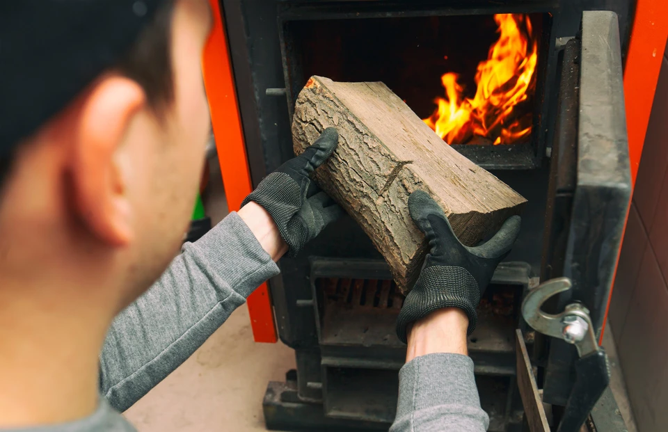 Intérieur chaleureux avec poêle à bois en fonte noire allumé, flammes oranges visibles