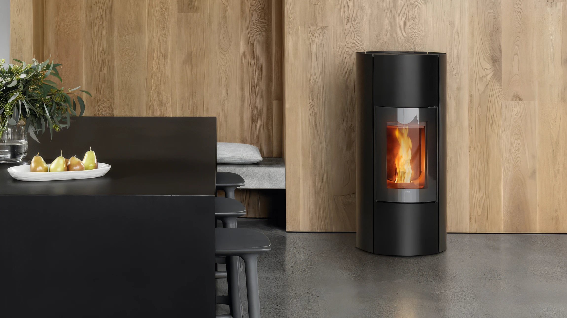 Intérieur rustique chaleureux avec poêle à bois en fonte noire allumé, flammes visibles derrière vitre arquée